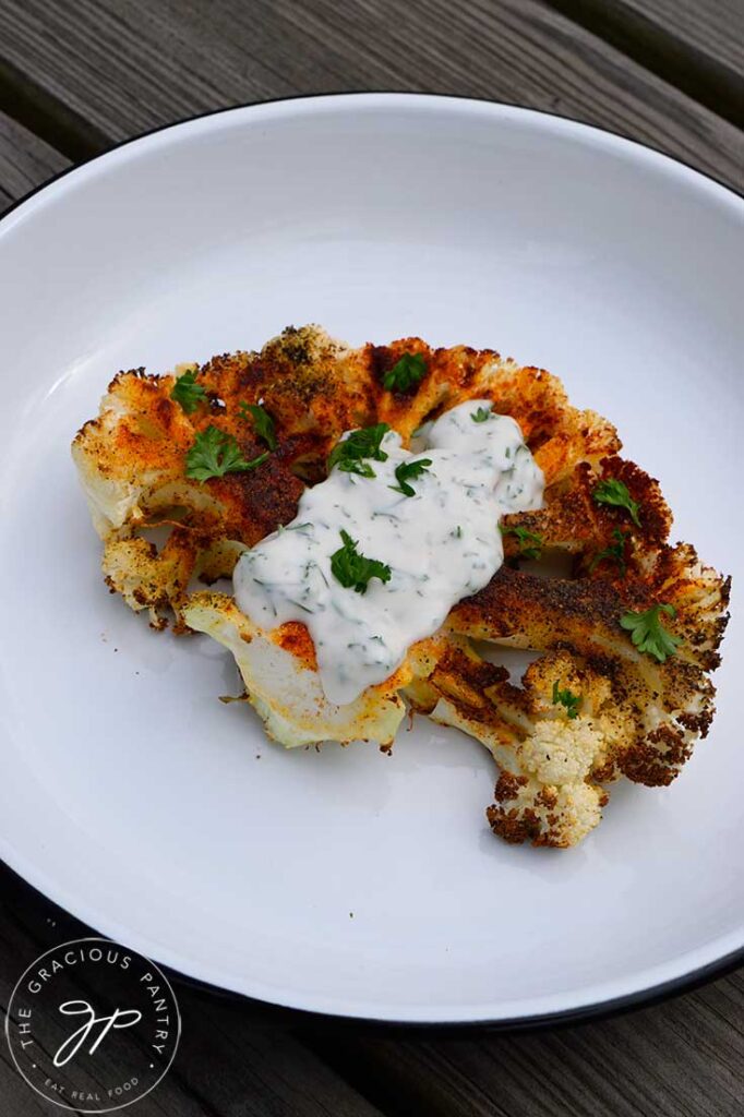 A front view of a single Air Fryer Cauliflower Steak with yogurt sauce on top.