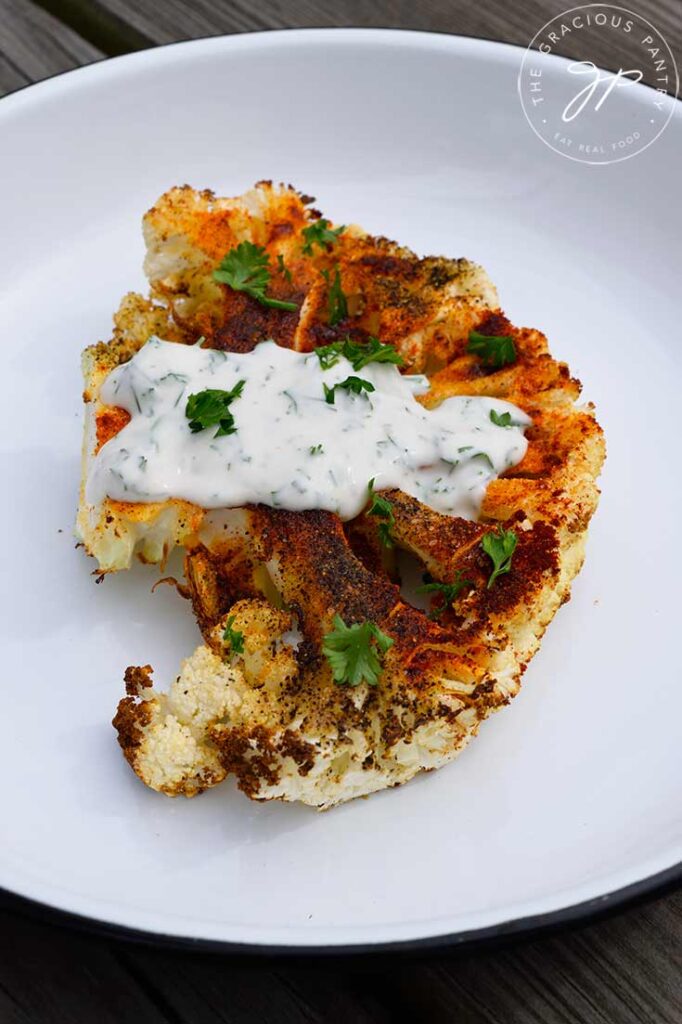 A side view of a Air Fryer Cauliflower Steak with yogurt sauce.