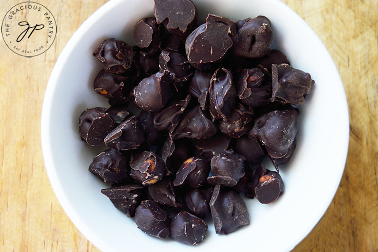 An overhead view looking down into a white bowl filled with Chocolate Covered Chickpeas.