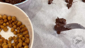 Separating chocolate covered chickpeas on a piece of parchment paper.