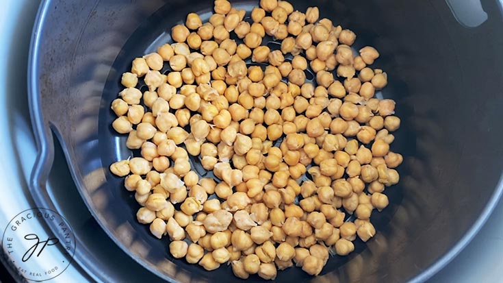 Cooked chickpeas sitting in an air fryer basket.