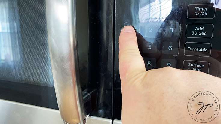 Setting a microwave to cook for 1 minute.