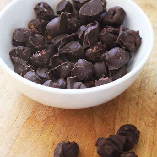 A white bowl filled with Chocolate Covered Chickpeas.