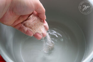 Adding salt to a pot of water.