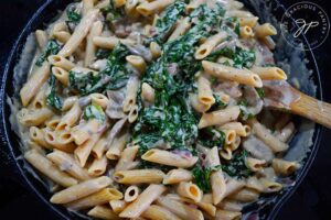 Creamy Kale And Mushroom Pasta stirred together in a cast iron skillet.