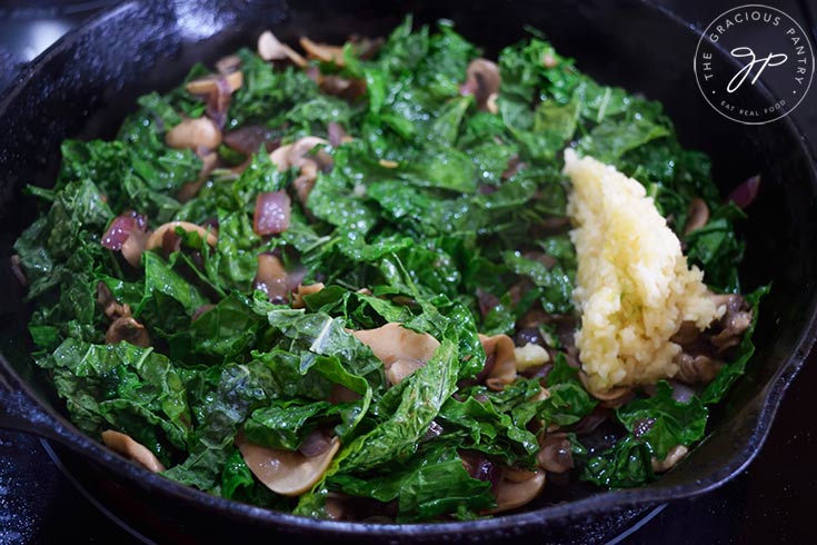 Pressed garlic added to sautéing vegetables in a skillet.