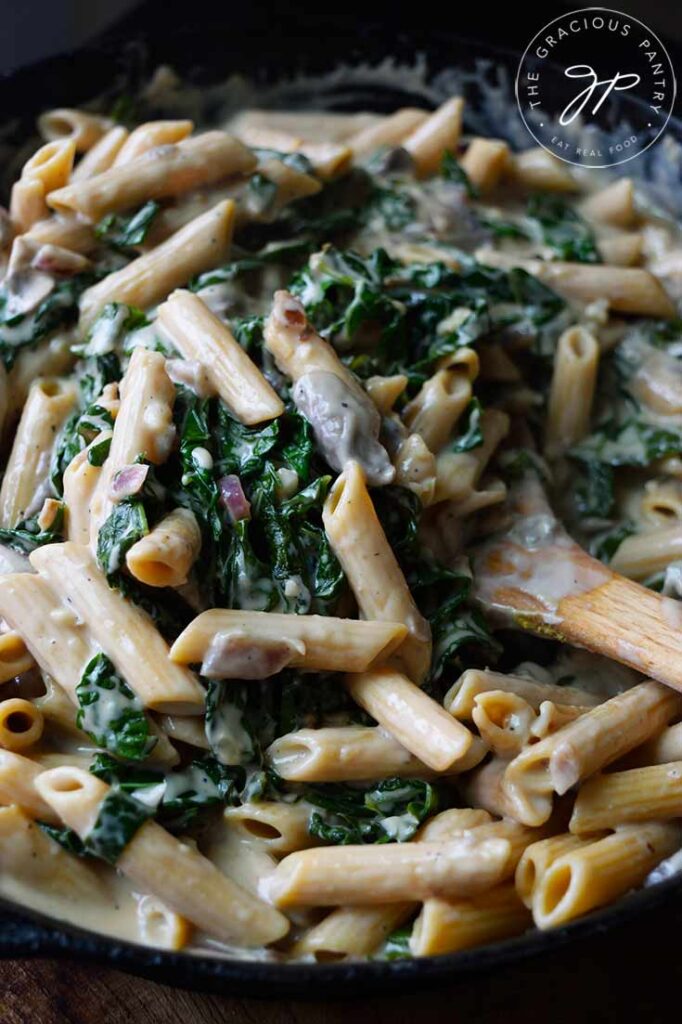 A closeup of Creamy Kale And Mushroom Pasta in a cast iron skillet.