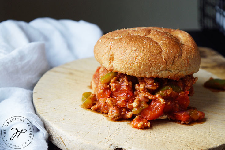 A fully assembled Healthy Turkey Sloppy Joe sits on a cutting board.