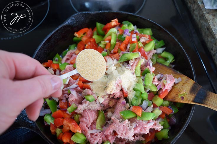 Adding garlic powder to Healthy Turkey Sloppy Joes filling.