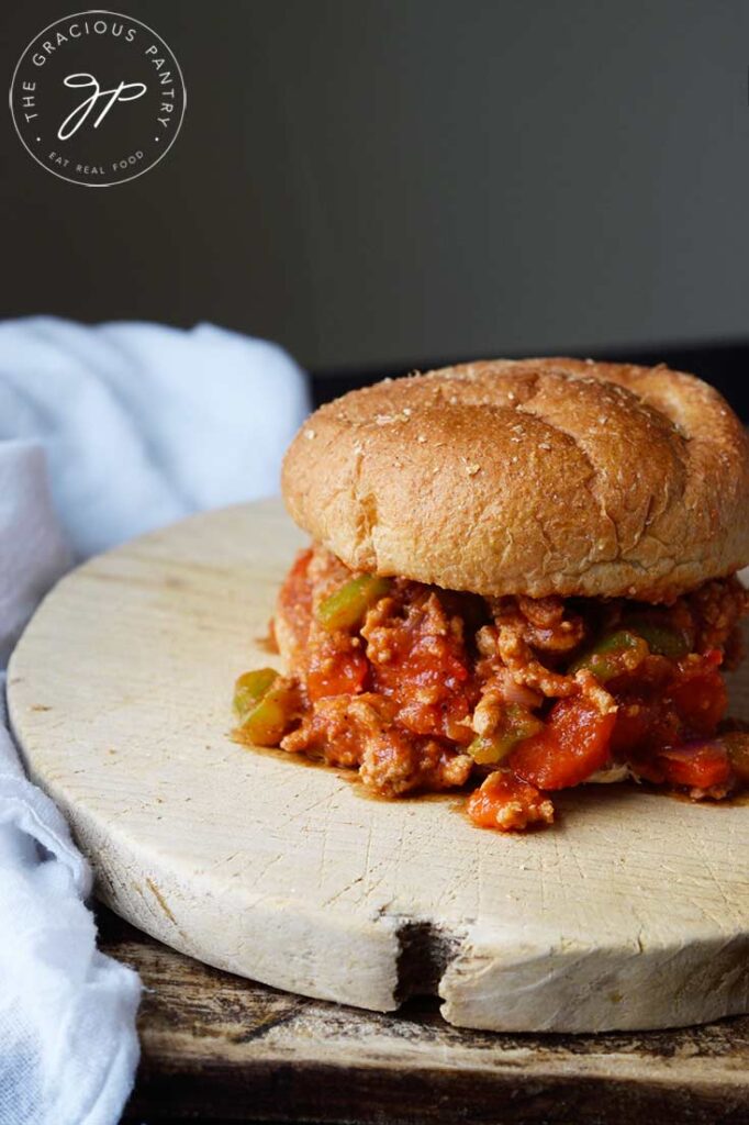 A single Healthy Turkey Sloppy Joe sits on two cutting boards with a white towel laying next to them.