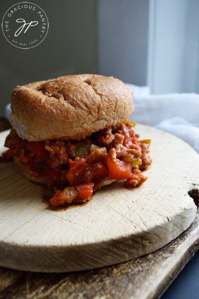A single Healthy Turkey Sloppy Joe sits on two cutting boards next to a white towel.