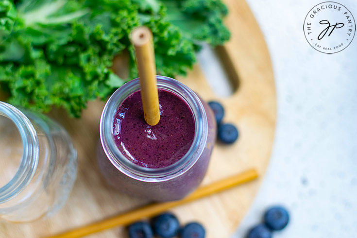 An overhead view of a glass jar filled with Kale Blueberry Smoothie.