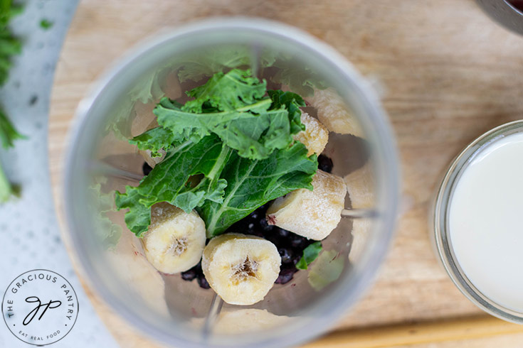 Kale Blueberry Smoothie Recipe ingredients sitting, unblended, in a blender tumbler.