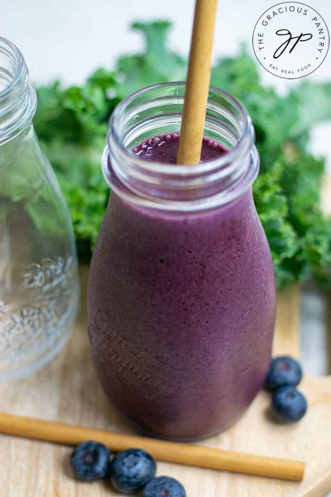 A close-up of a small milk jar filled with Kale Blueberry Smoothie.