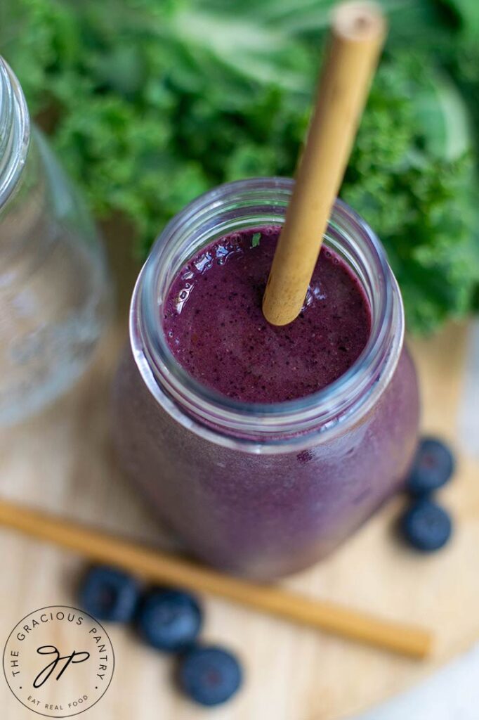 A slightly angled, overhead view of a small milk jug filled with Kale Blueberry Smoothie.