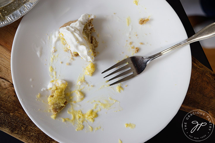 Nothing but crumbs, and a single bite of lemon cream pie left behind on a white plate with a fork.