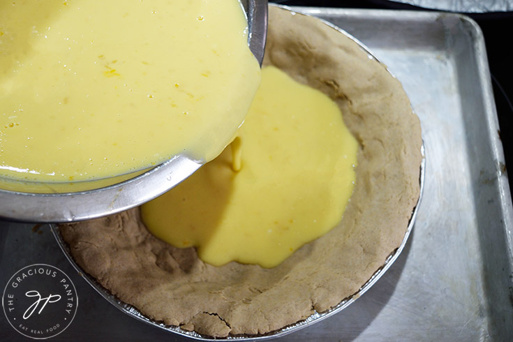 Pouring lemon cream pie filling into a pre-baked crust.