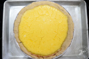 A just-baked lemon cream pie without topping, sits cooling in the fridge.