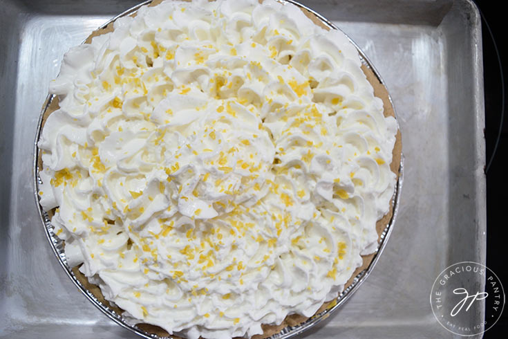 A chilled lemon cream pie topped with fresh whipped cream and sprinkled with fresh lemon zest.