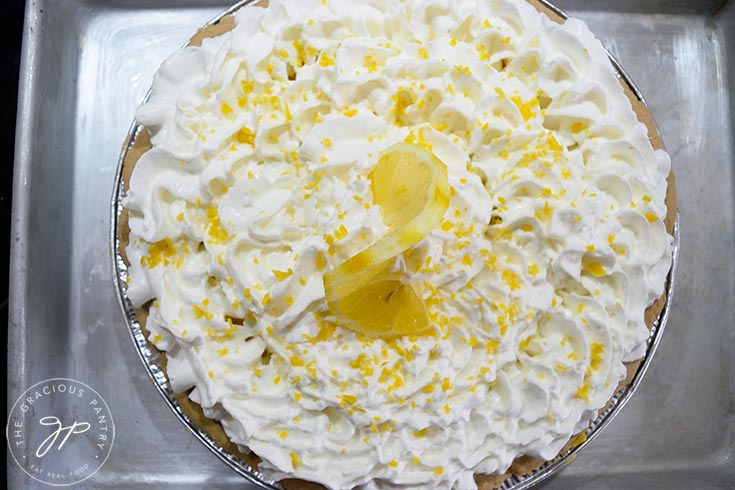 A lemon cream pie garnished with a lemon slice, artfully arranged in the center of the pie.