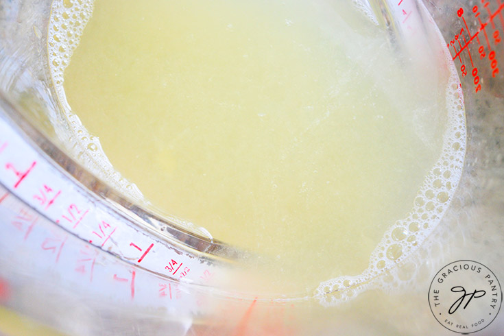 A measuring cup holding three-quarters of a cup of fresh lemon juice.