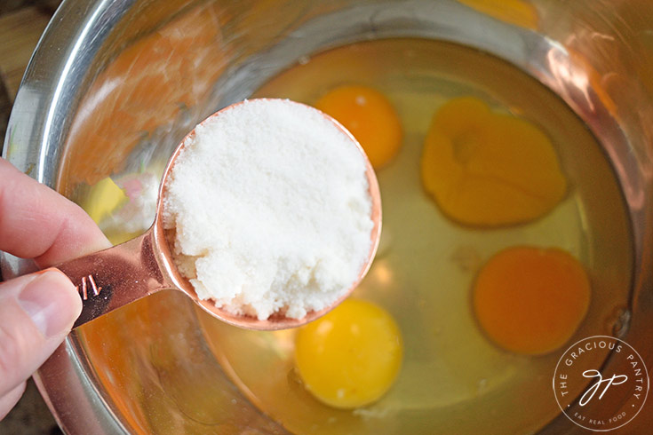 Adding sweetener to eggs in a mixing bowl.