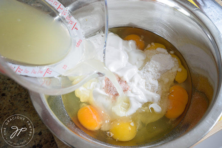Pouring lemon juice into a mixing bowl of various ingredients for this recipe for lemon cream pie.