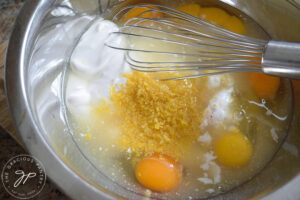 Ingredients sitting in a bowl, unmixed, with a whisk.