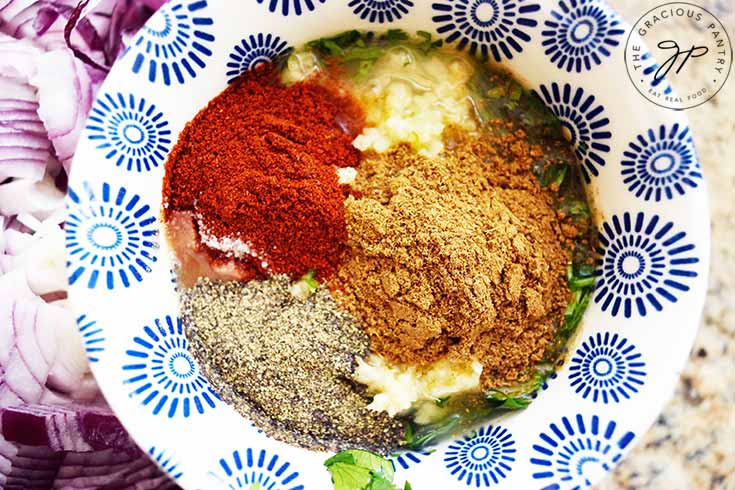 Spices in a small mixing bowl with pressed garlic, fresh cilantro and lime juice.