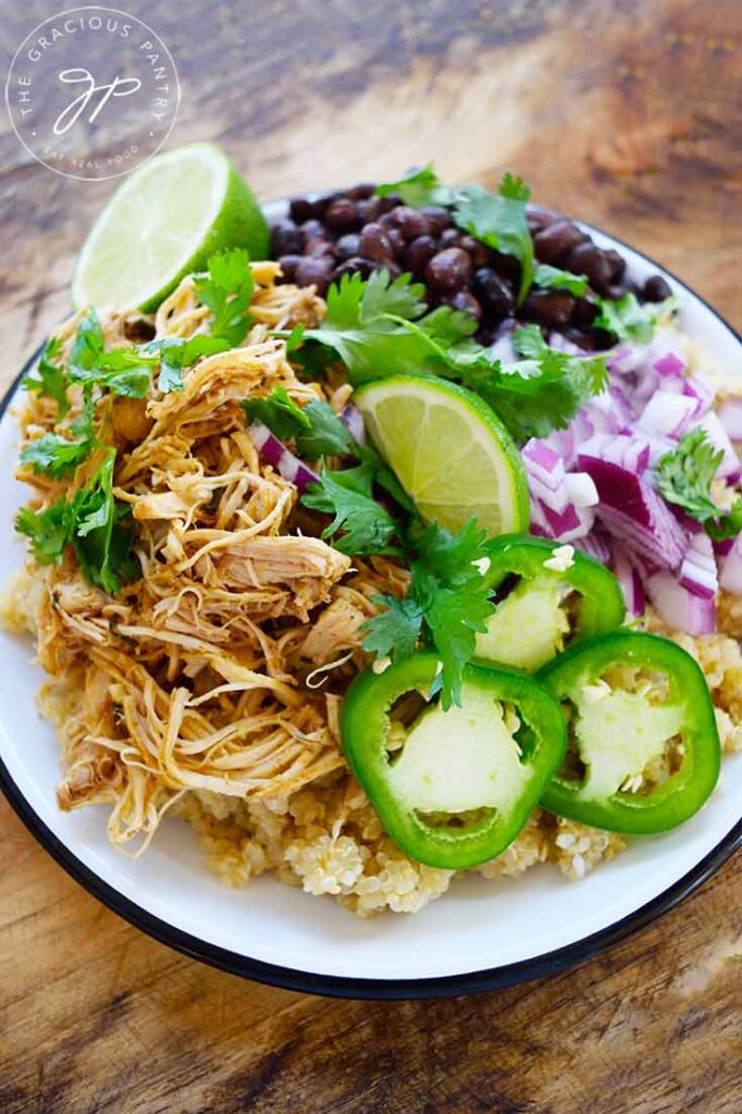 A plat of garnished Slow Cooker Cilantro Lime Chicken sits on a wood cutting board.