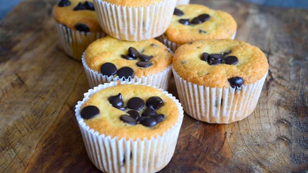 Several almond flour muffins sitting together on a wood surface.