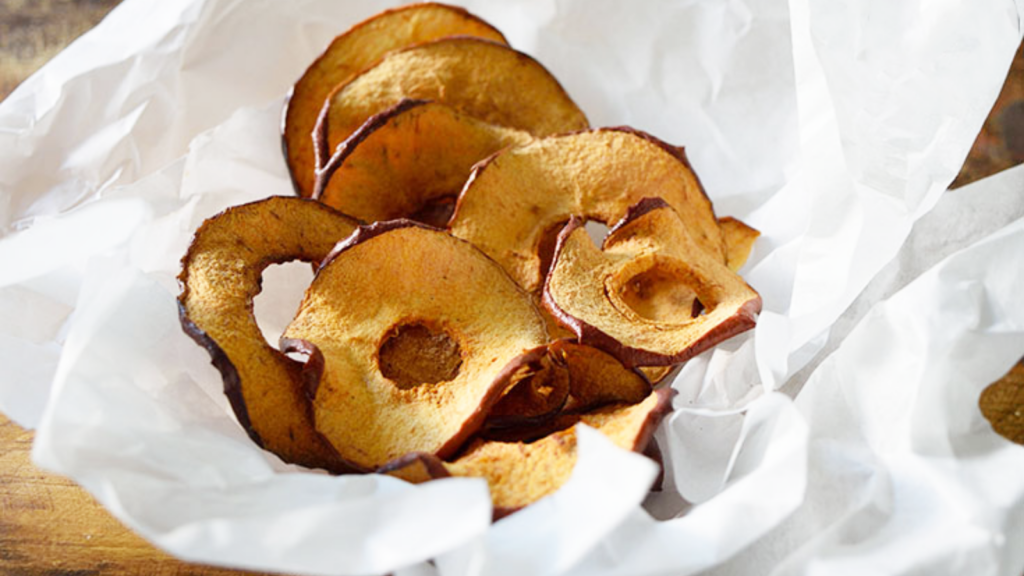 Parchment paper holds a bowlful of apple chips.