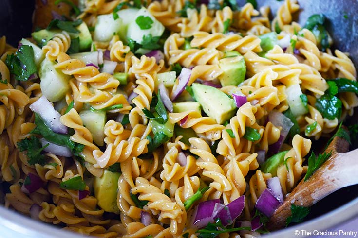 A close up of a large mixing bowl filled with Avocado Pasta Salad.