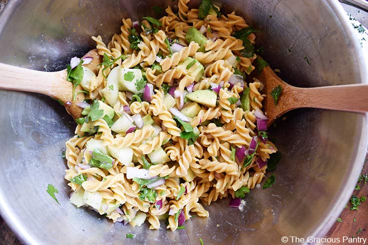 Finished Avocado Pasta Salad tossed in a large, metal mixing bowl.