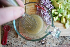 Whisking dressing in a glass measuring cup with a wire whisk.
