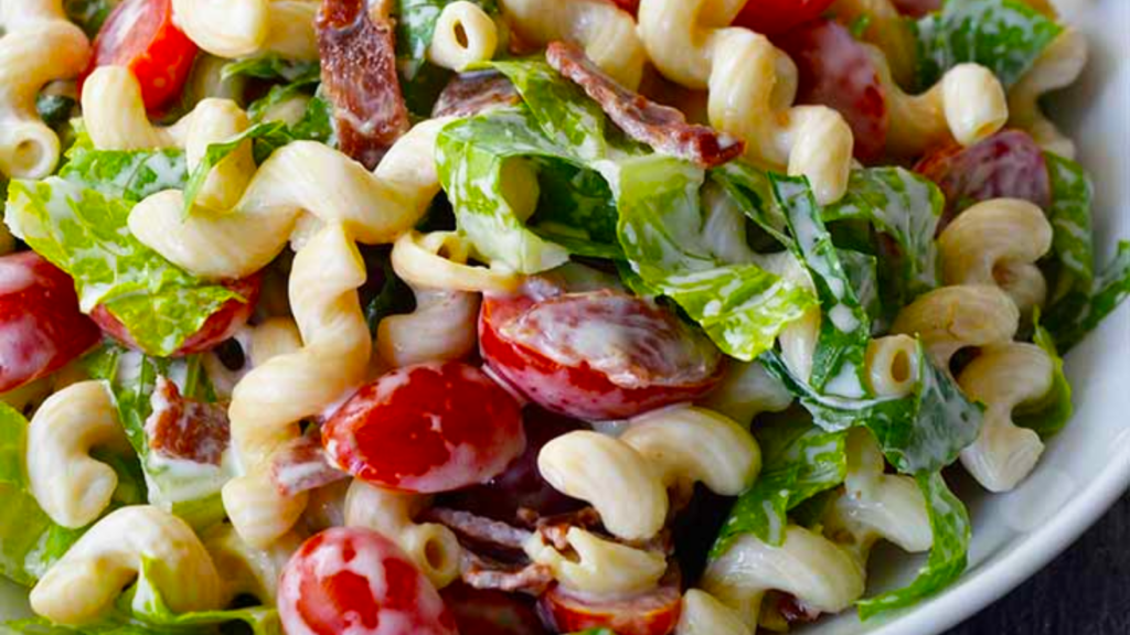 Closeup of a BLT pasta salad in a white bowl.