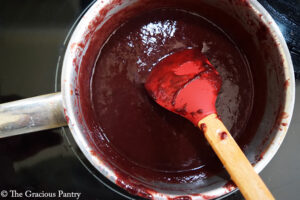 The blended Blueberry BBQ Sauce sitting in a pot with a red rubber spatula.