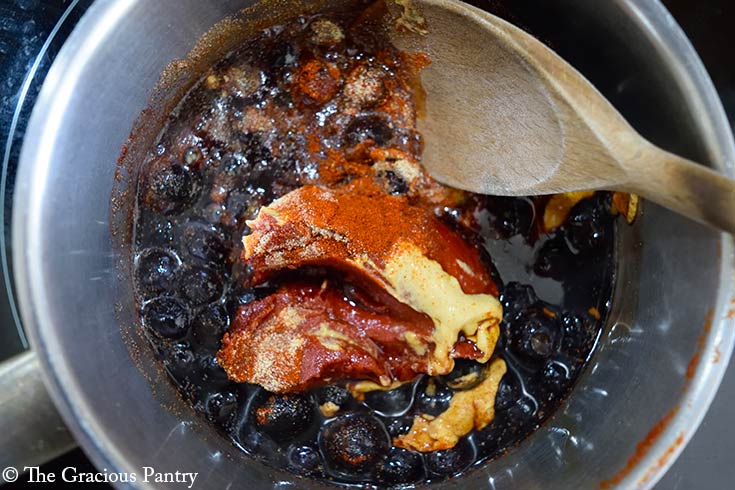 Blueberry BBQ Sauce Recipe ingredient in a pot with a wooden spoon.