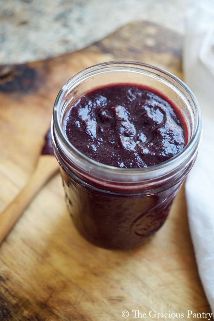 A side view of an open canning jar filled with Blueberry BBQ Sauce.