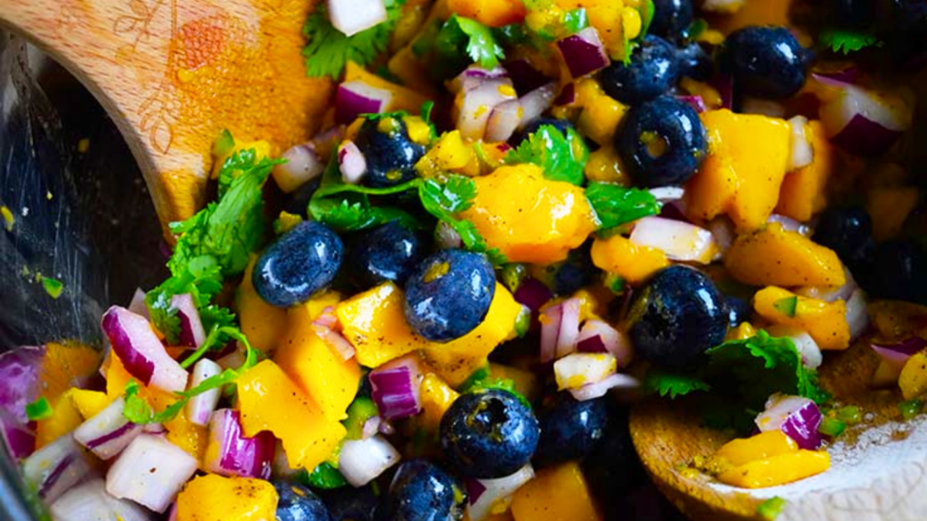 A closeup of blueberry mango salsa in a mixing bowl.