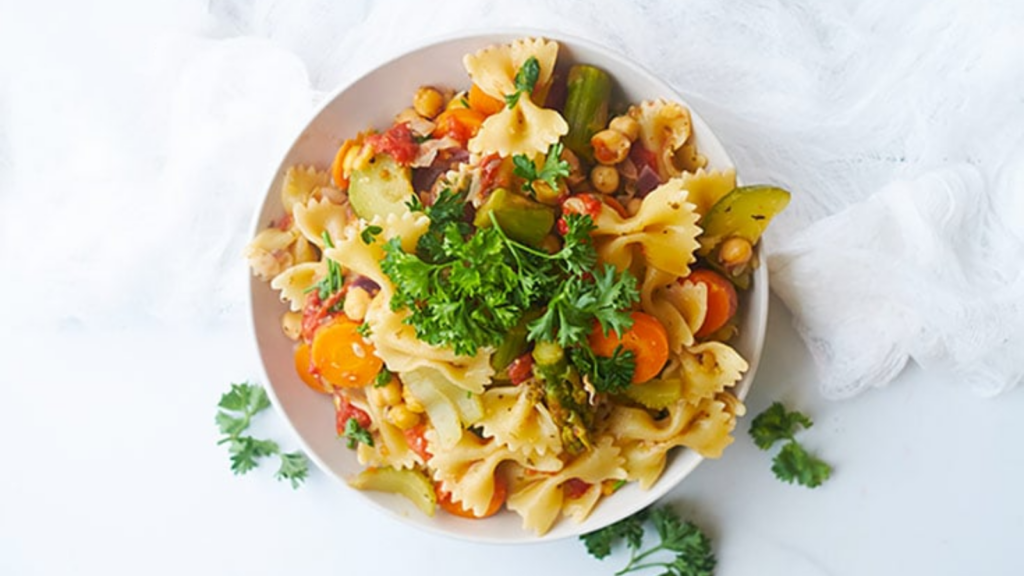 Overhead view of Bow Tie Pasta Salad in a white bowl and garnished with fresh parsley.