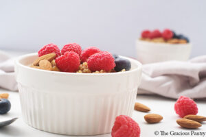 A white bowl of Breakfast Quinoa with fresh raspberries and blueberries.