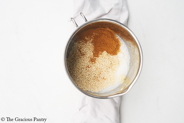 Cinnamon, quinoa, and milk added to a pot of mashed banana.