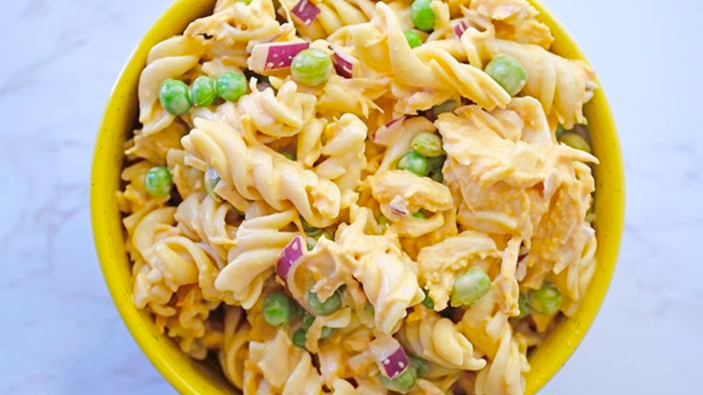 A closeup of a yellow bowl filled with buffalo chicken pasta salad.