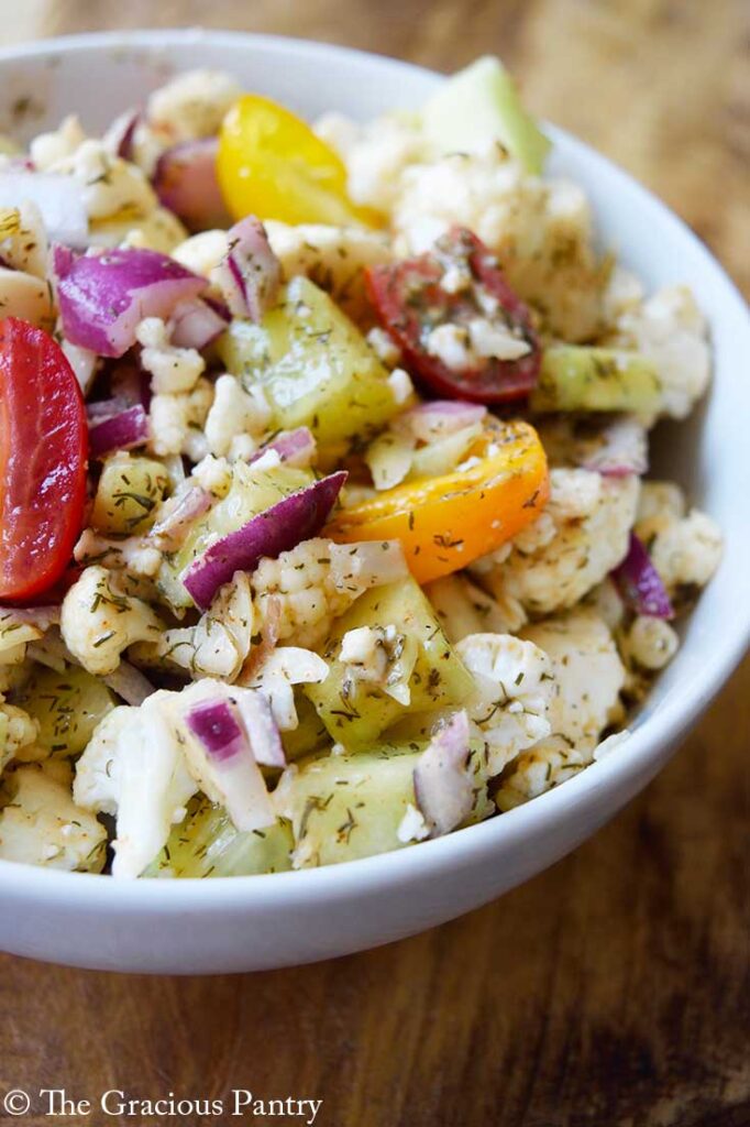 A side angle of cauliflower salad served in a white bowl.