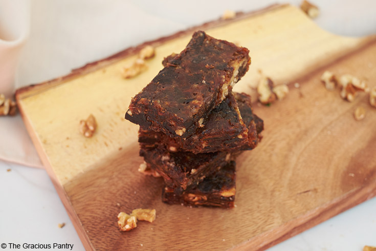 A stack of Cherry Pie Lara Bars sit on a wood cutting board.