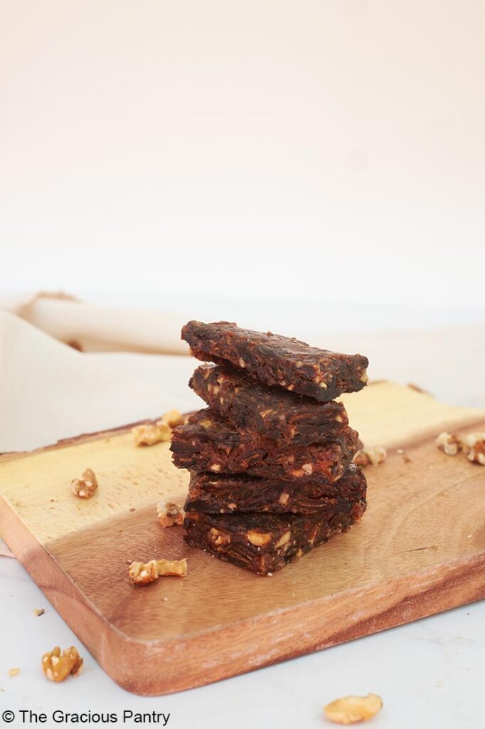 A side view of a stack of Cherry Pie Lara Bars sitting on a wood cutting board.