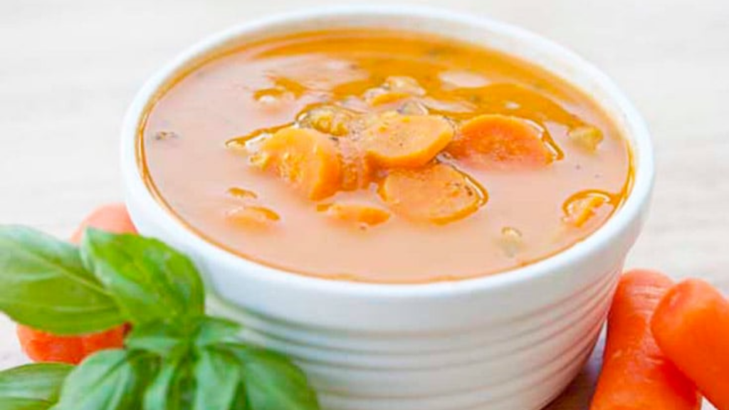 A white bowl sits filled with cherry tomatoe soup.