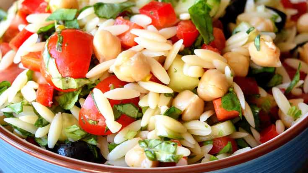 A closeup of a blue bowl filled with chickpea orzo pasta salad.