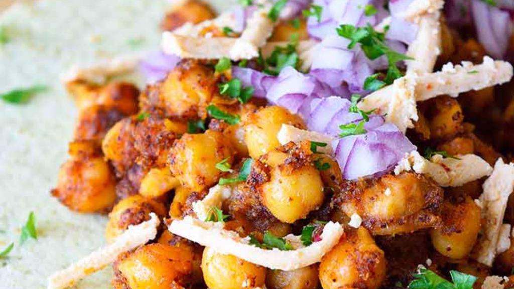 A closeup of a Chickpea Taco that lays open on a wood surface.